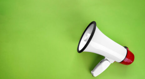 Megaphone on color background