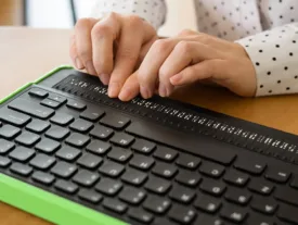 Des mains de femmes qui parcours un lecteur d'écran en braille.