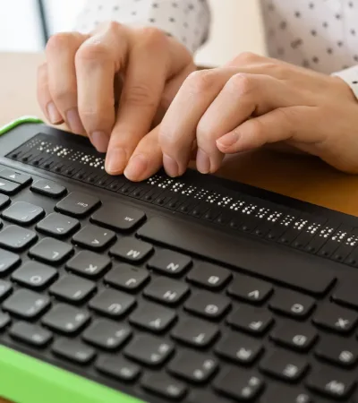 Des mains de femmes qui parcours un lecteur d'écran en braille.
