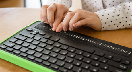 Des mains de femmes qui parcours un lecteur d'écran en braille.