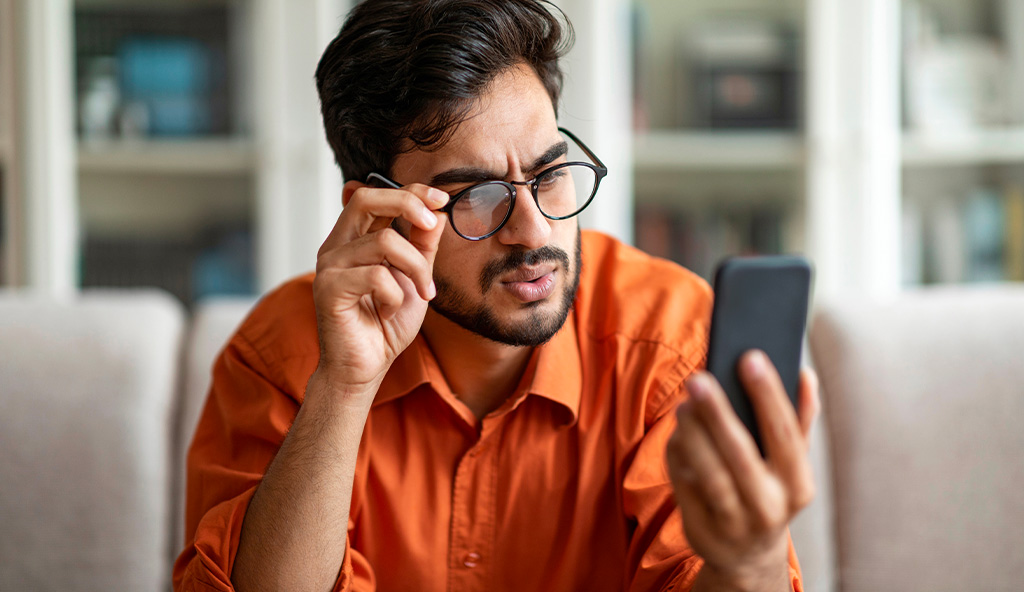 Un homme regarde une info sur son portable avec un air très dubitatif.